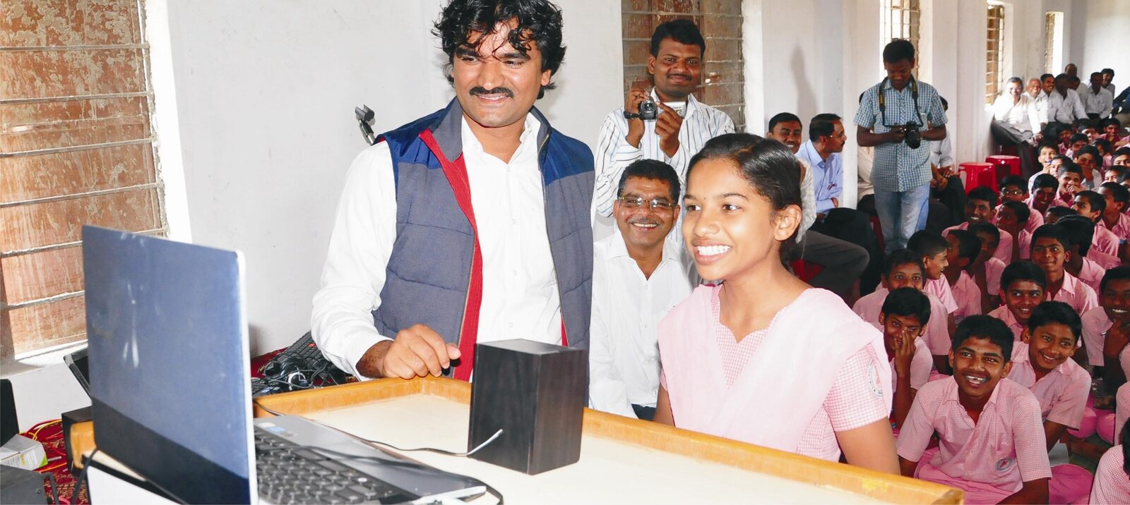 Founder leading a Global Classroom session with a student in front of a full school assembly.