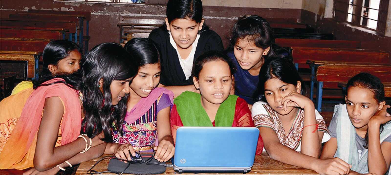Girls gathered around a laptop during a Global Classroom session.