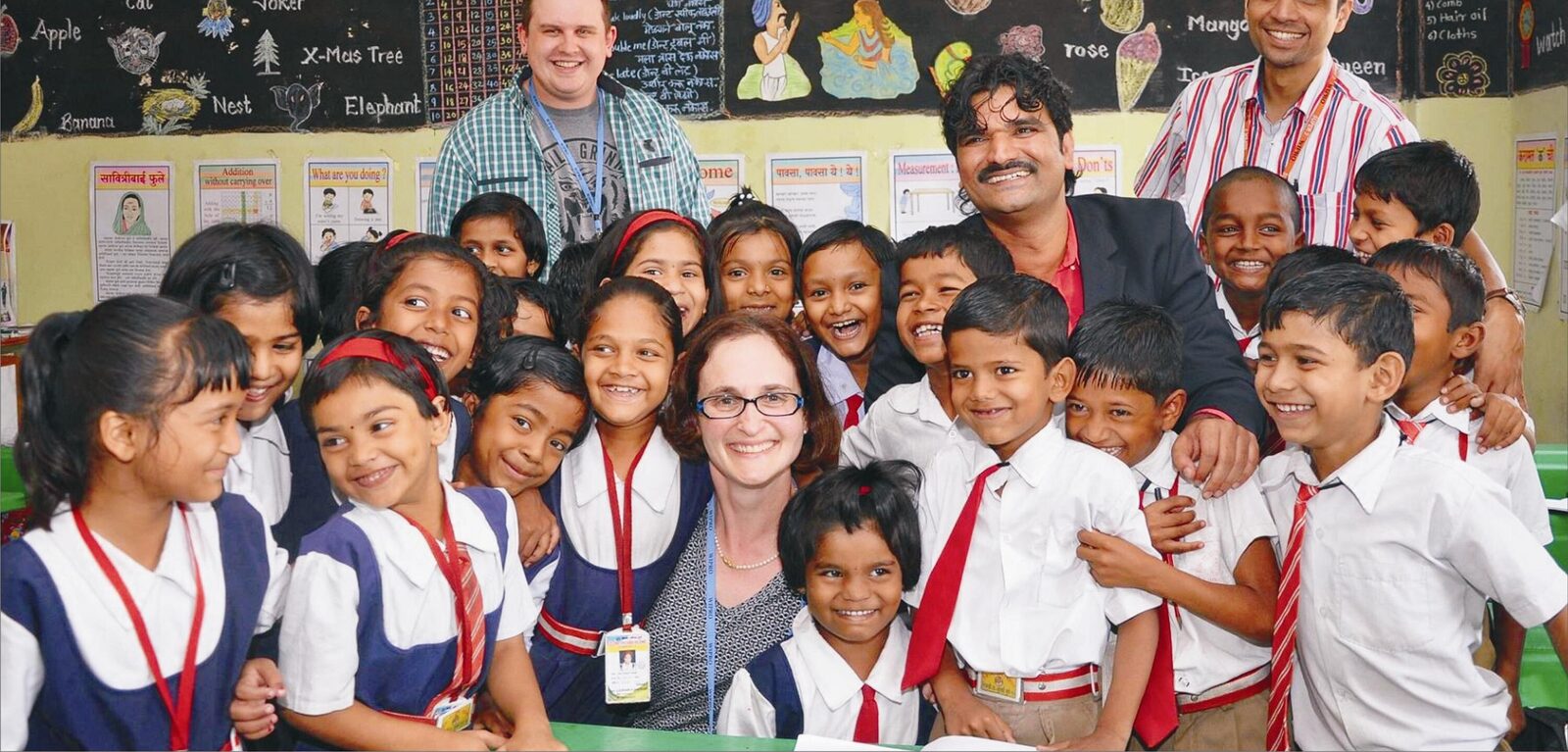 International volunteers and a school teacher with students in a Global Classroom.